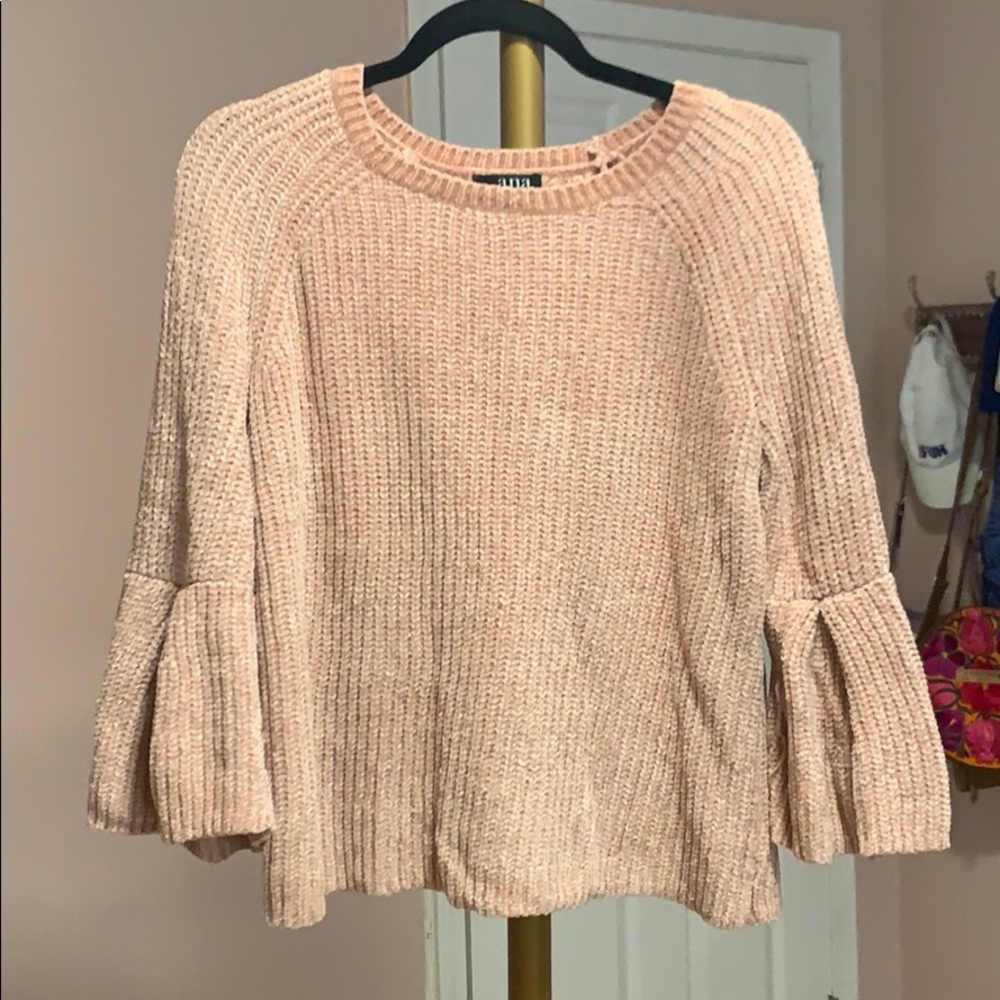 pink sweater with ruffles on sleeves.